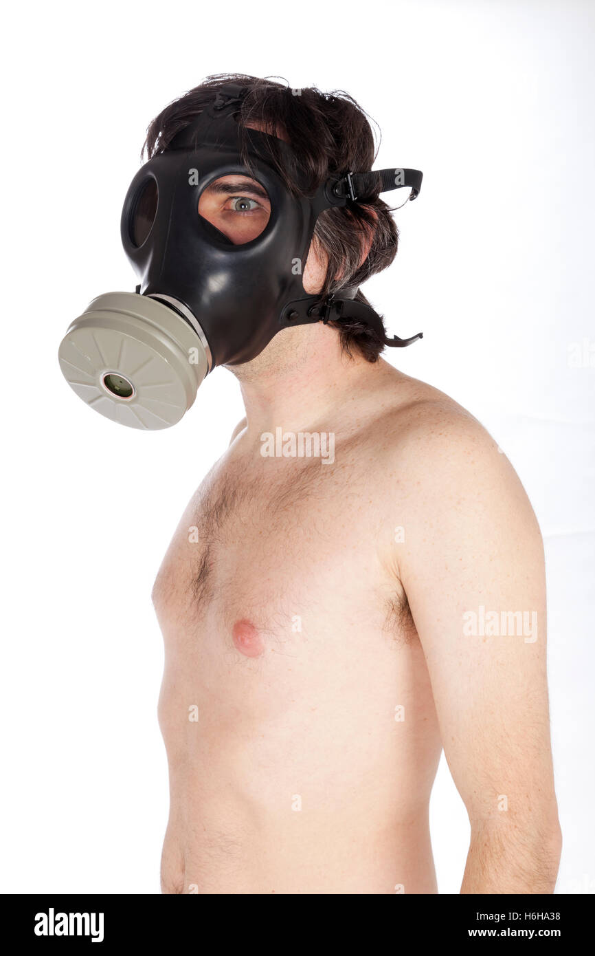 An adult Caucasian man in his early 30's topless and wearing a gas mask, a terrified expression in his eyes. Isolated on white b Stock Photo