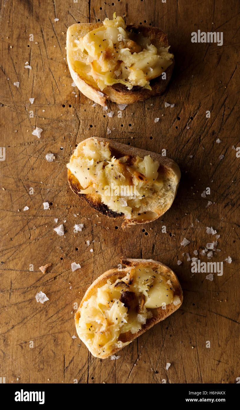 Crostini with mashed roasted  garlic  on rustic cutting board Stock Photo