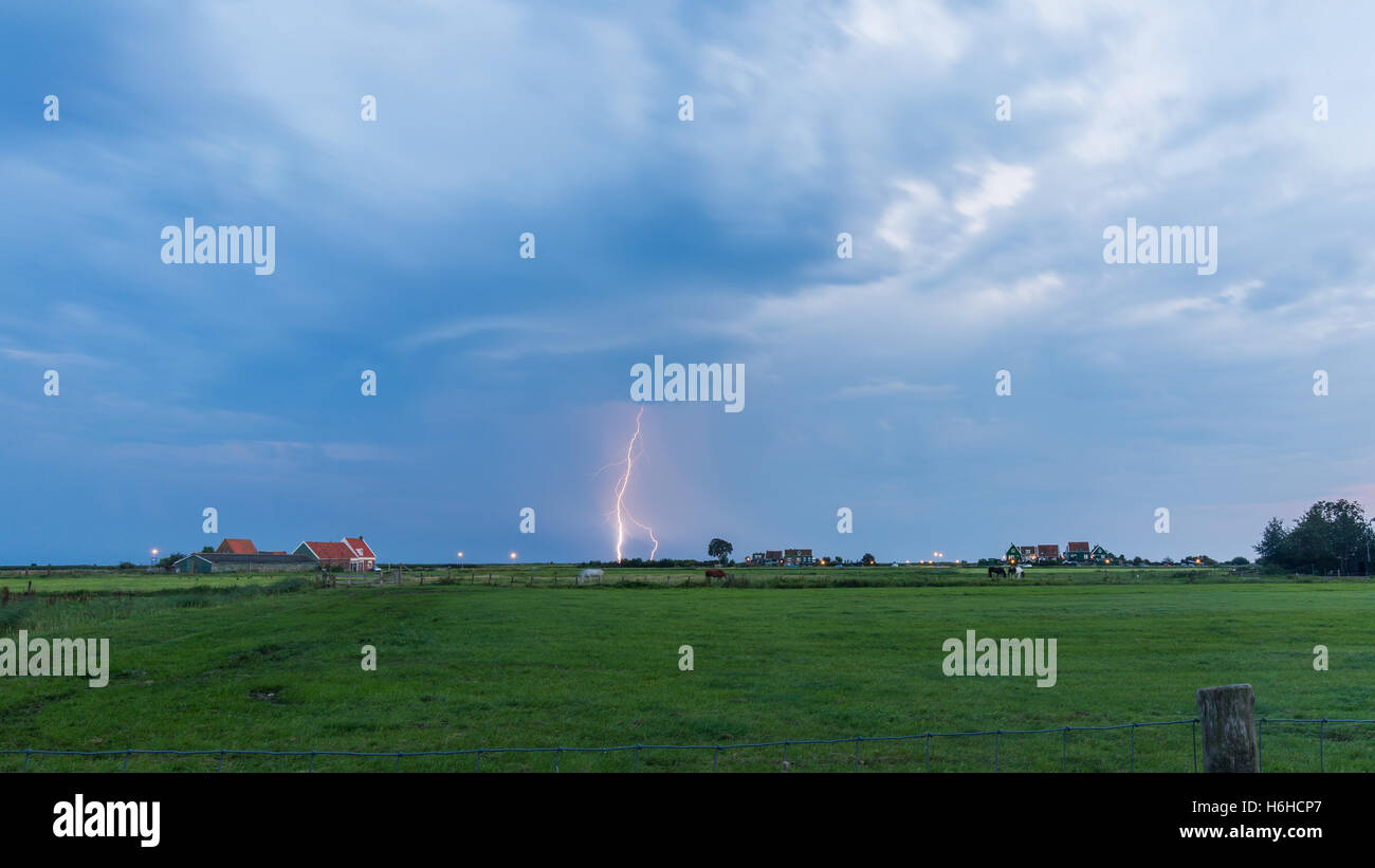 Thunderclouds cast a lightning bolt over farmland in the polder of Marken, The Netherlands Stock Photo