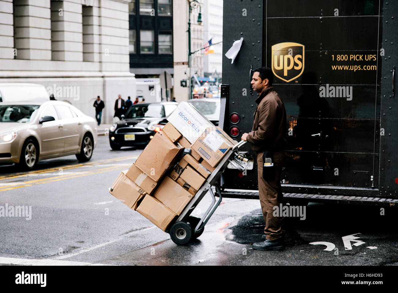 New-York - NOV 13: UPS delivery worker waiting by his truck to cross the street holding a cart full with packages in New-York, U Stock Photo