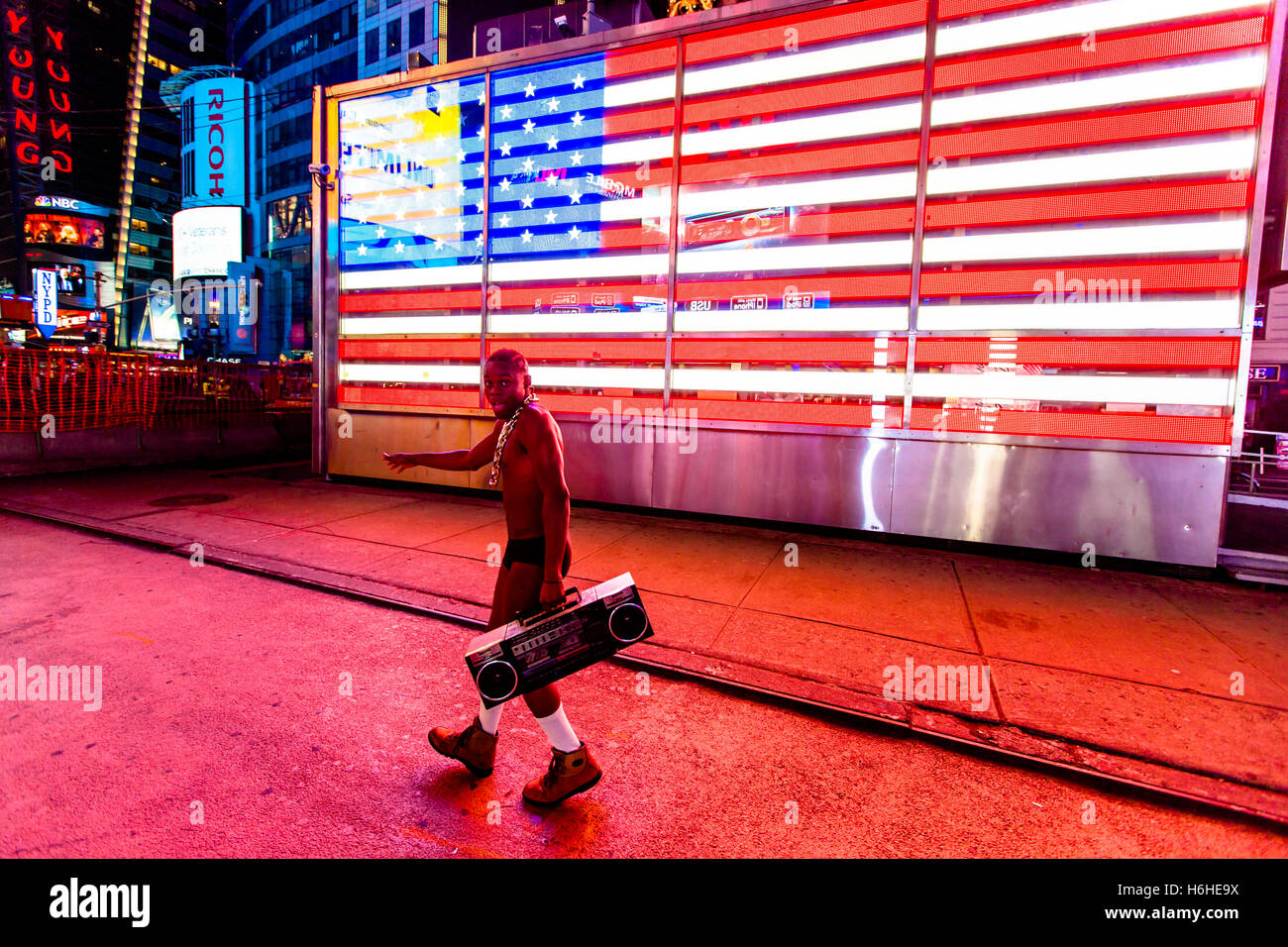 NEW YORK - NOV 11: Street performer in his underwear, holding a retro cassette player in front of the LED American flag in Times Stock Photo