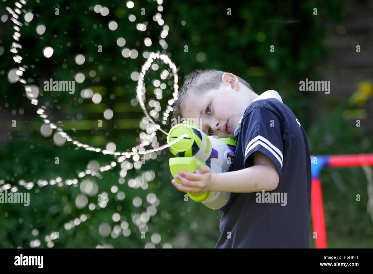 Young boy playing with water pistol. Water is backlit Stock Photo