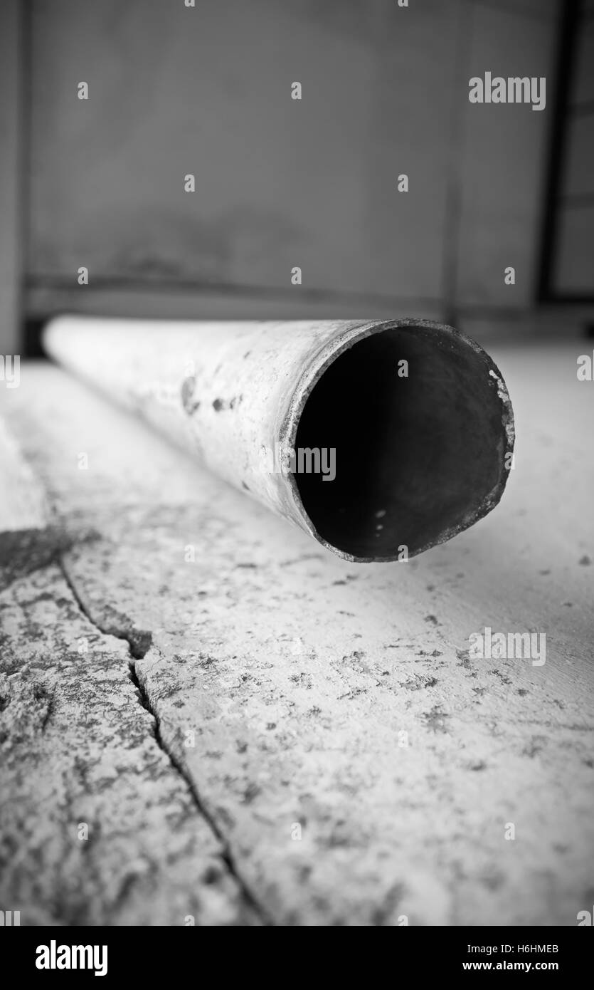 The end part of old drain water pipe down from the roof. Black and white photography. Stock Photo