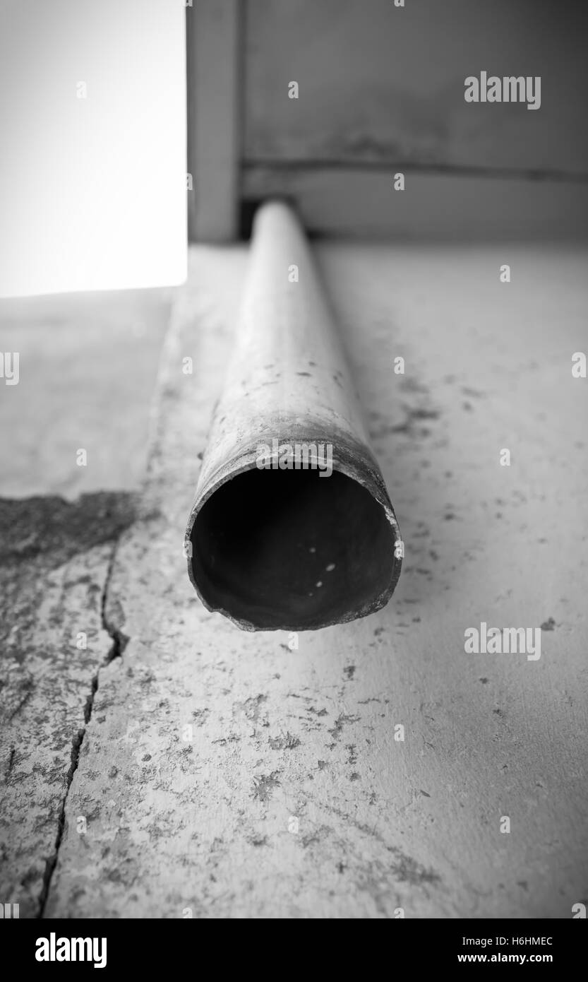 The end part of old drain water pipe down from the roof. Black and white photography. Stock Photo