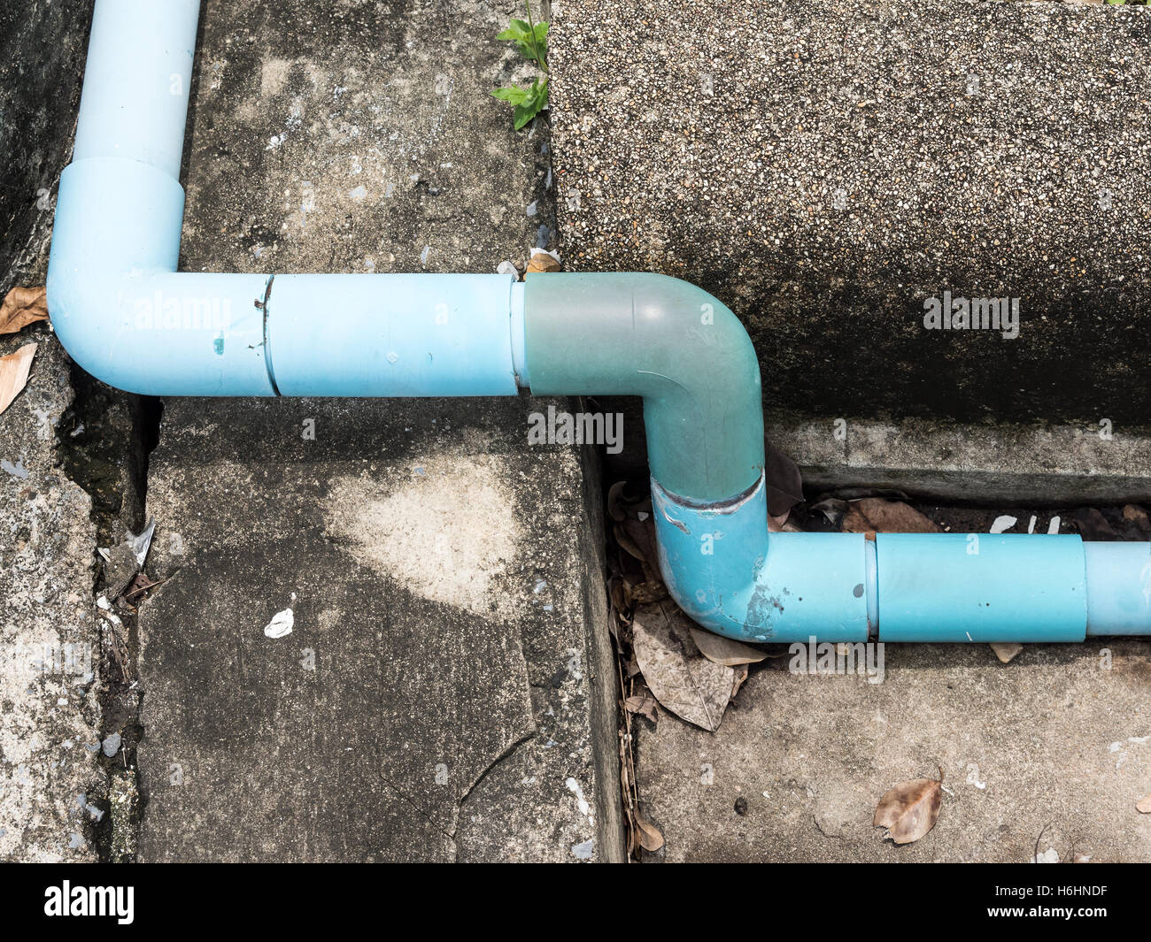 Old PVC pipe with elbow on the cement path near the builiding Stock