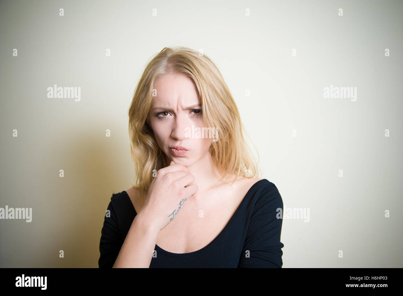 Young blond woman, doubtful and looking at camera copy space Stock Photo