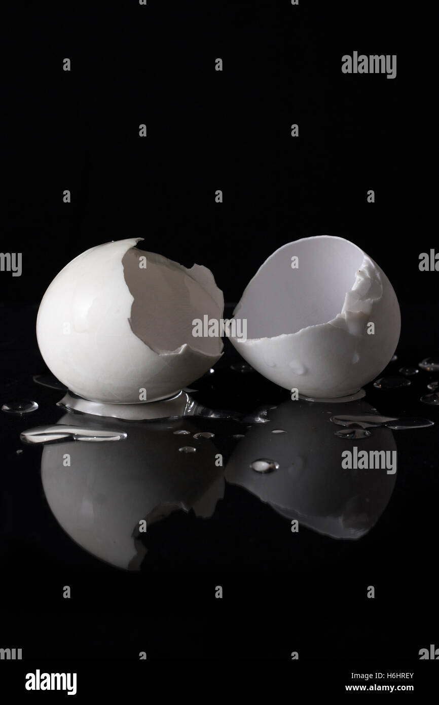 Cracked white egg shells isolated on black background with water drop