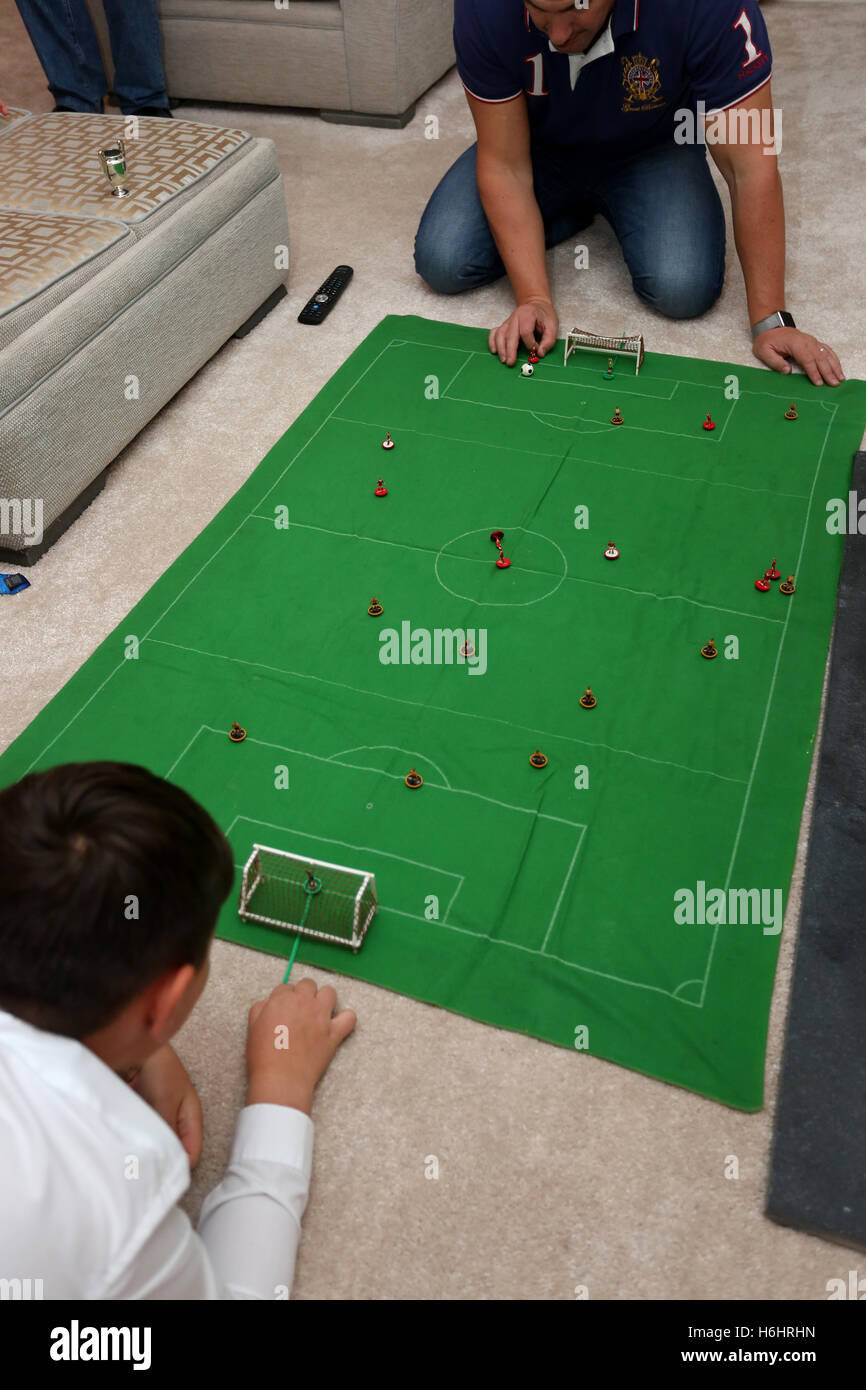 A father and his son pictured playing the Subbuteo football game in their lounge at home in Leeds, West Yorkshire, UK. Stock Photo
