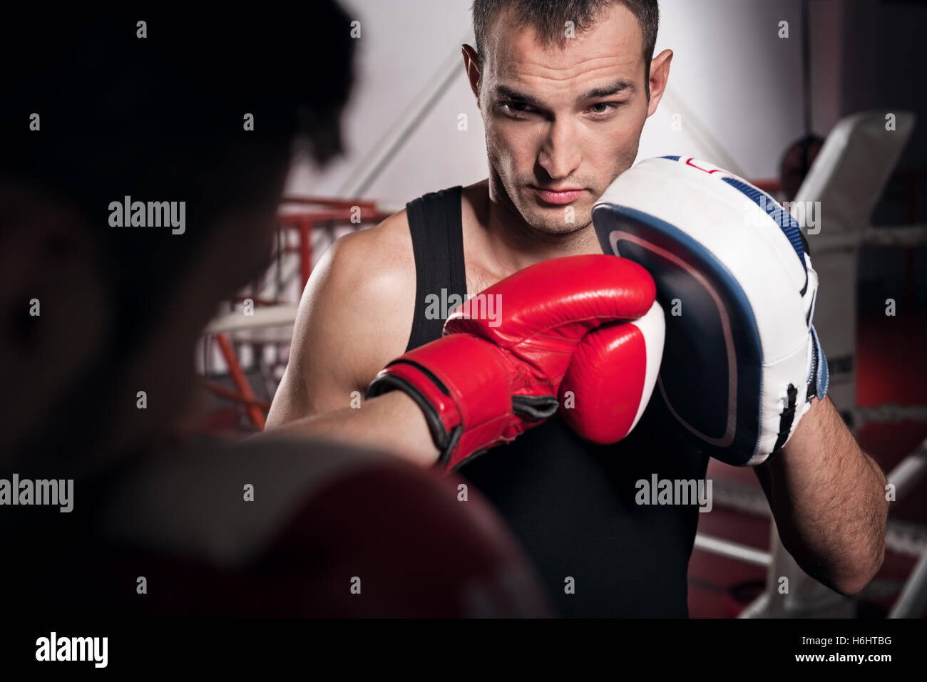 Young trainer holding boxing pad Stock Photo - Alamy