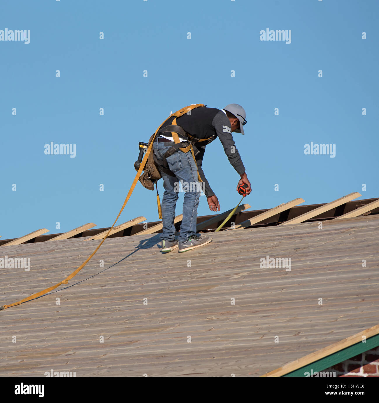 Florida USA Roofer wearing a safety harness and holding a tape measure to  fix wooden slats on a pitched roof Stock Photo - Alamy