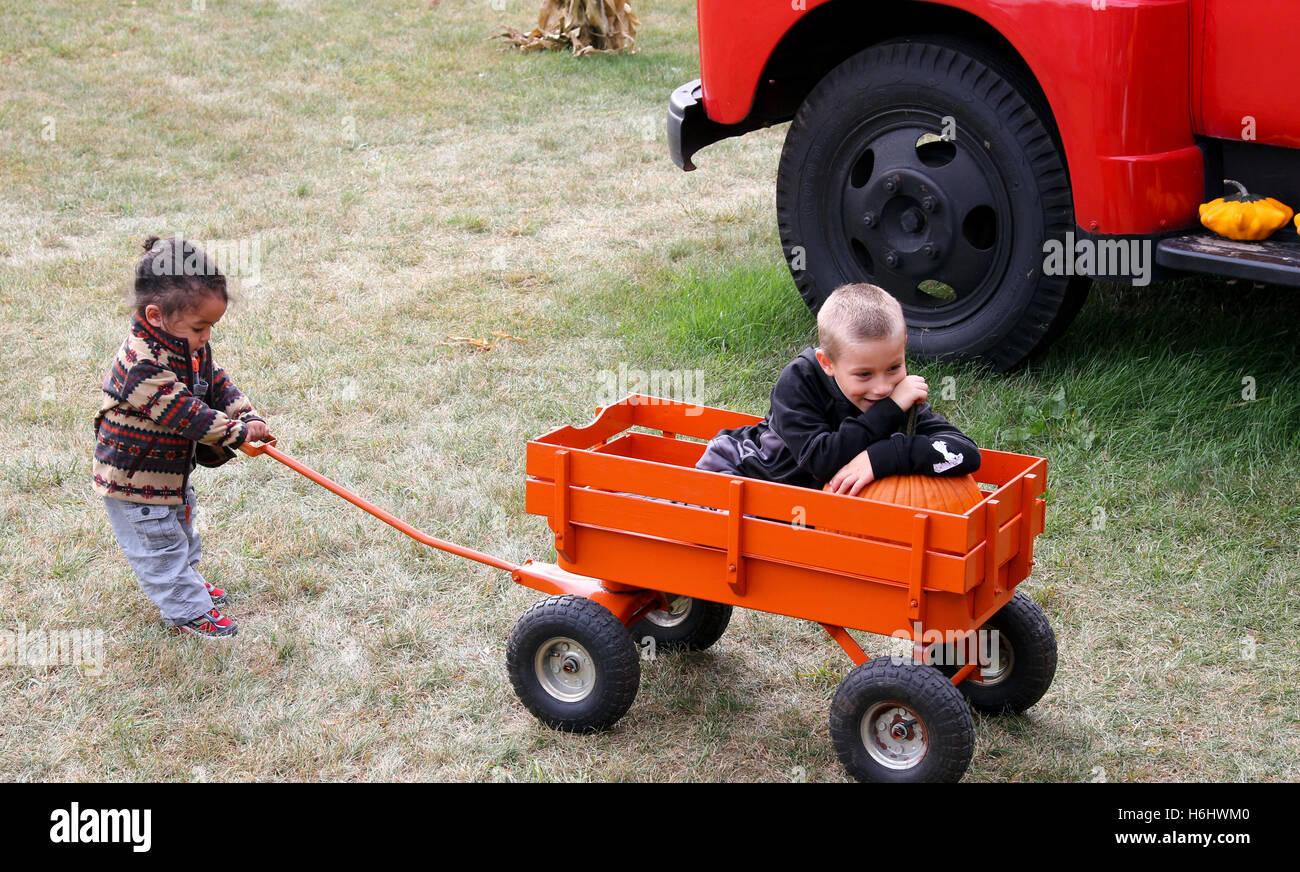 Sister pulling brother in a little wagon Stock Photo - Alamy