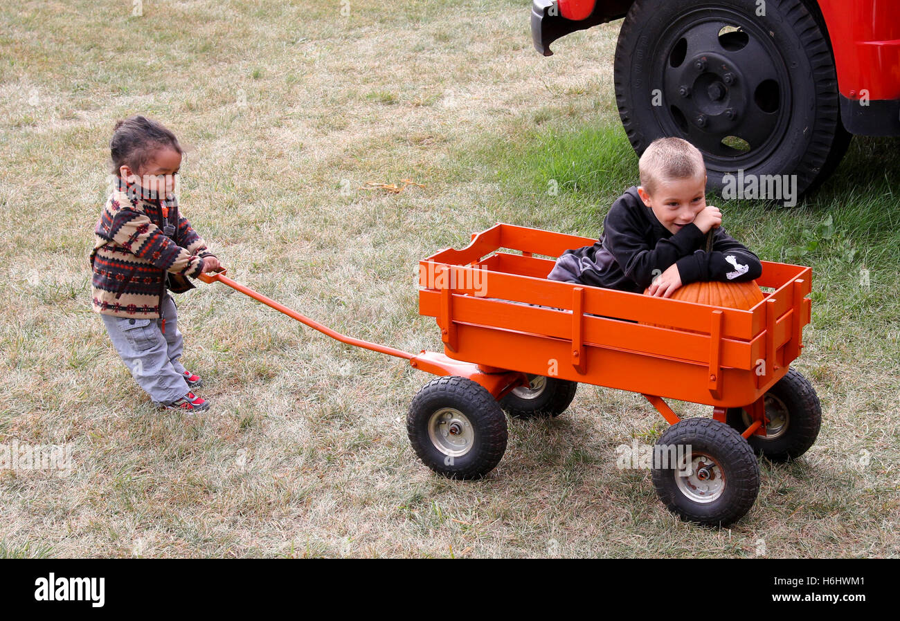 Sister pulling brother in a little wagon Stock Photo - Alamy