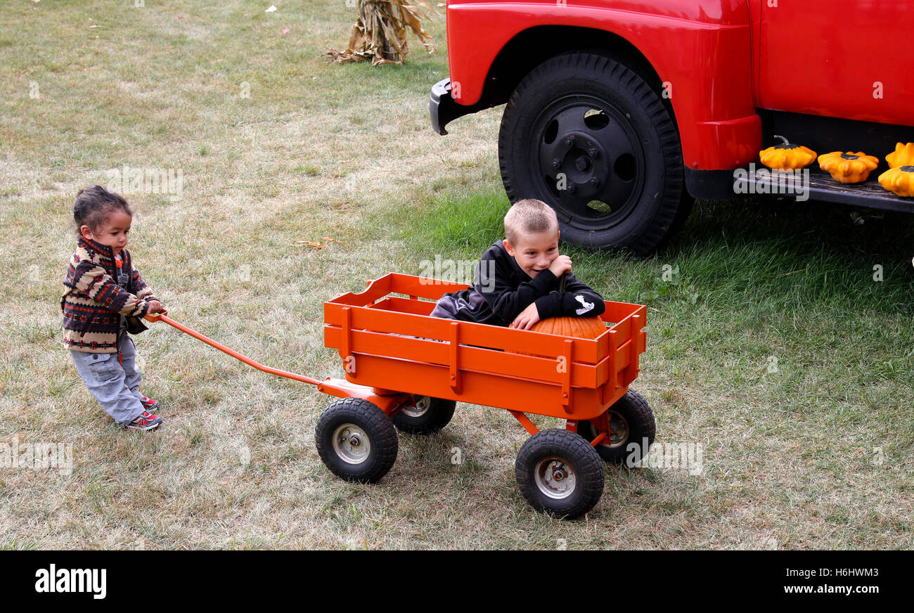 Sister pulling brother in a little wagon Stock Photo - Alamy