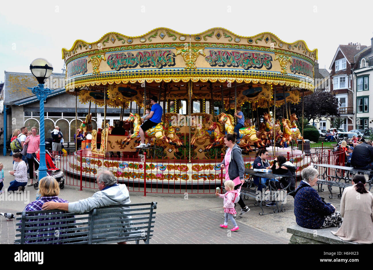 Dorset - Weymouth sea front fairground scene - galloping horses carousel - visitors having fun - colour and movement - holidays Stock Photo