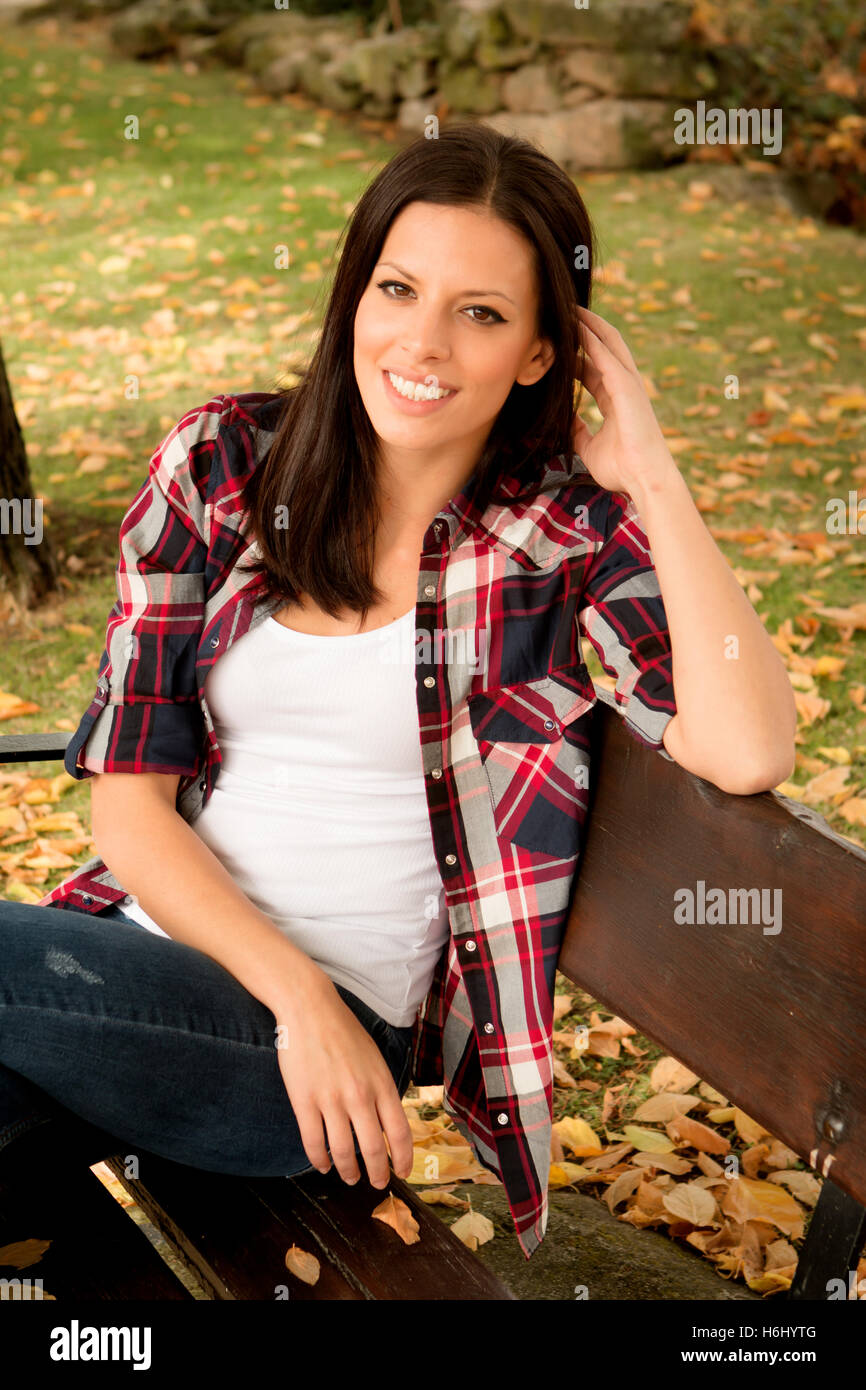 Beautiful young woman sitting on a bench in park at fall Stock Photo ...