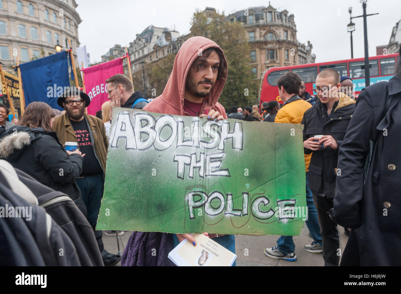 London, UK. 29th October 2016. A man holds a poster 'Abolish the Police' as he waits to march with the Families and friends of people killed by police or in prisons. Peter Marshall/Alamy Live News Stock Photo