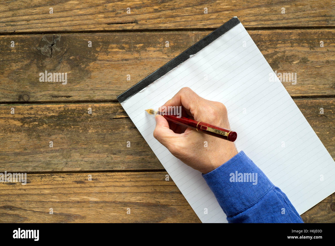 Man s hand writing with a fountain pen wooden background stock photo