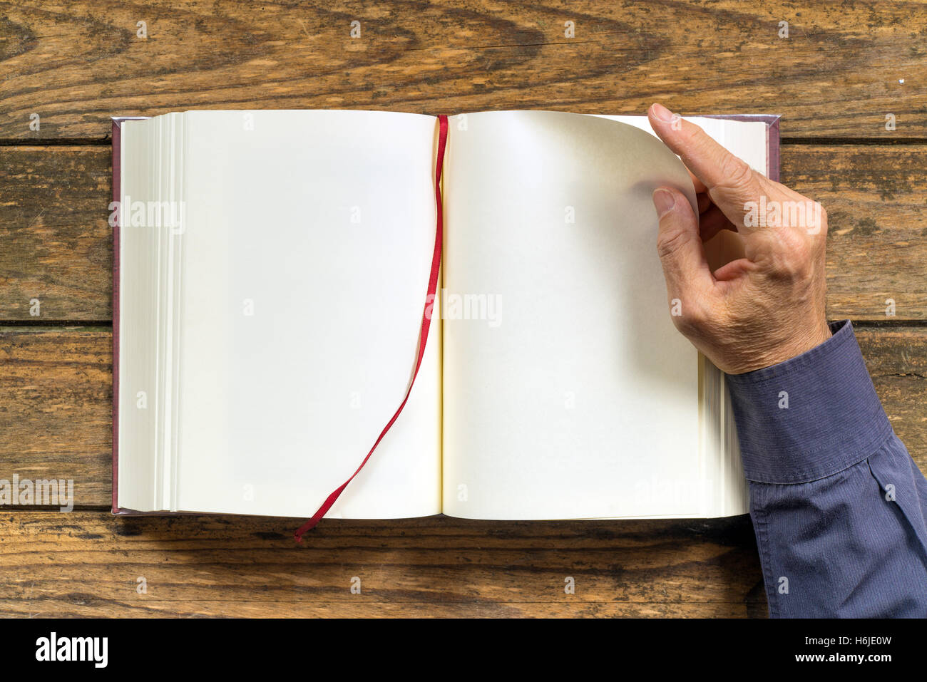 a man's hand turns the page of a blank book. Copy space. Wooden background Stock Photo