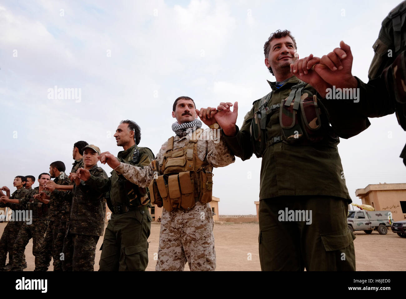 Kurdish fighters of the People's Protection Units YPG dancing traditional Kurdish dance in a military recruitment ceremony in Al Hasakah or Hassakeh district in northern Syria Stock Photo