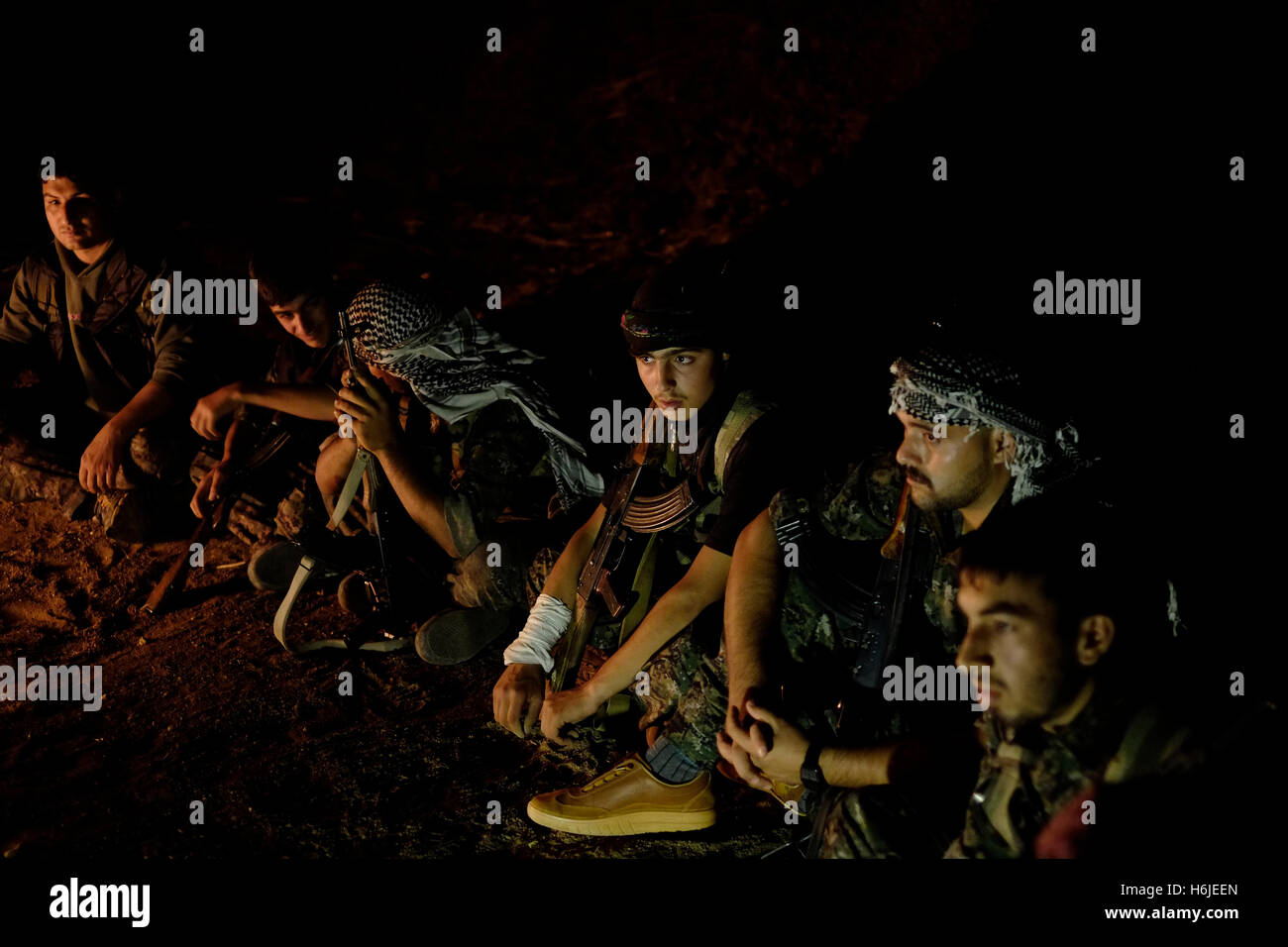 Fighters of the YPG Kurdish People's Protection Unit siting around a bonfire at night in Al Hasakah or Hassakeh district in Rojava the de facto Kurdish autonomous region originating in and consisting of three self-governing cantons in northern Syria Stock Photo