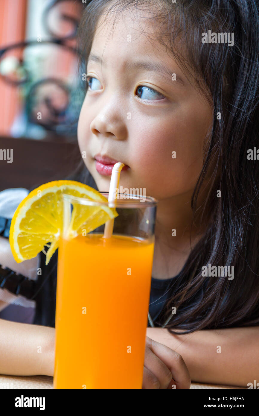 Little girl drinking fresh orange juice in glass Stock Photo - Alamy