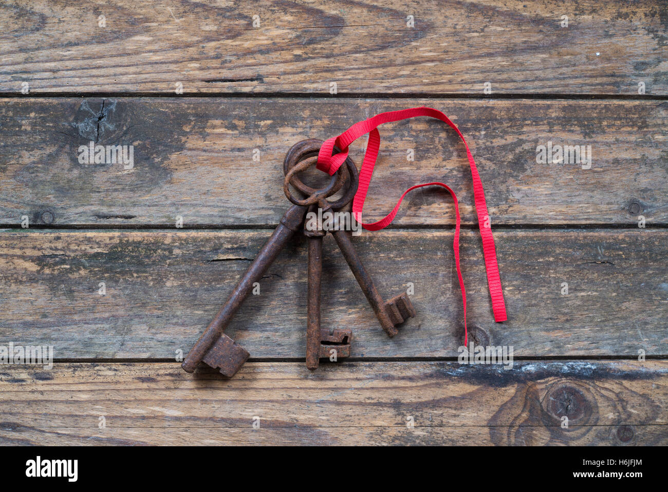 three keys tied with a red ribbon on wooden background Stock Photo - Alamy