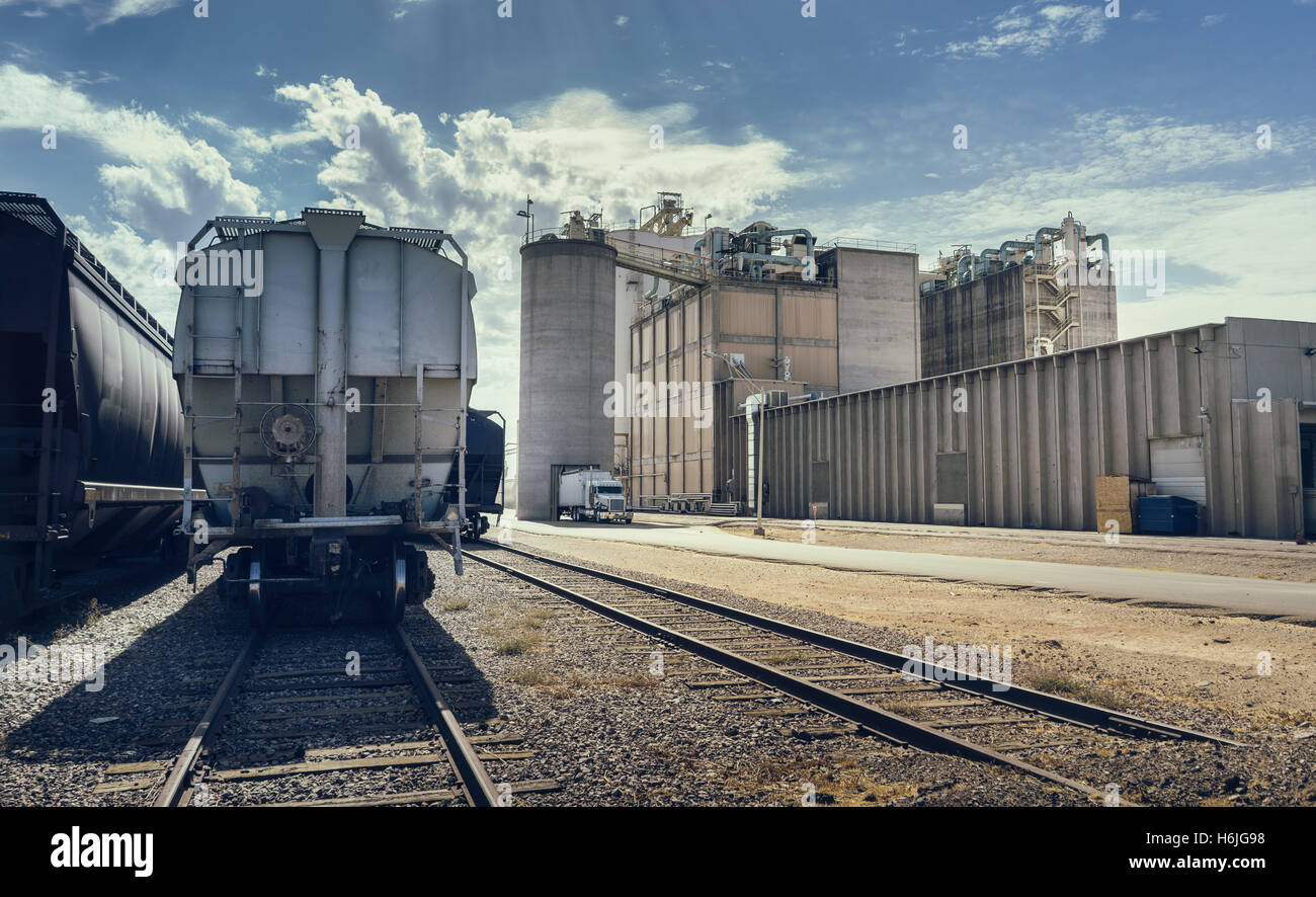Desert landscape. Arizona heat beats down on industrial building and rail road track with cargo containers, silo and large facil Stock Photo
