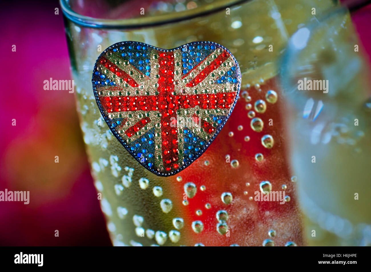 Concept heart shaped reflective sparkling Union Jack Flag motif with glasses of English sparkling wine behind Stock Photo