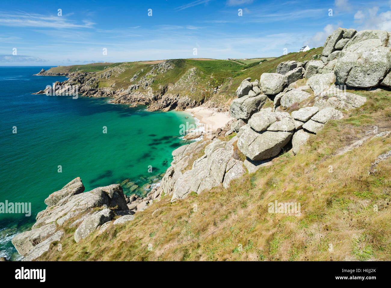 Turquoise sea, rocky cliffs at the bright sandy Porth Chapel Beach on Penwith Peninsula on the south coast of Cornwall, England, UK in summer Stock Photo