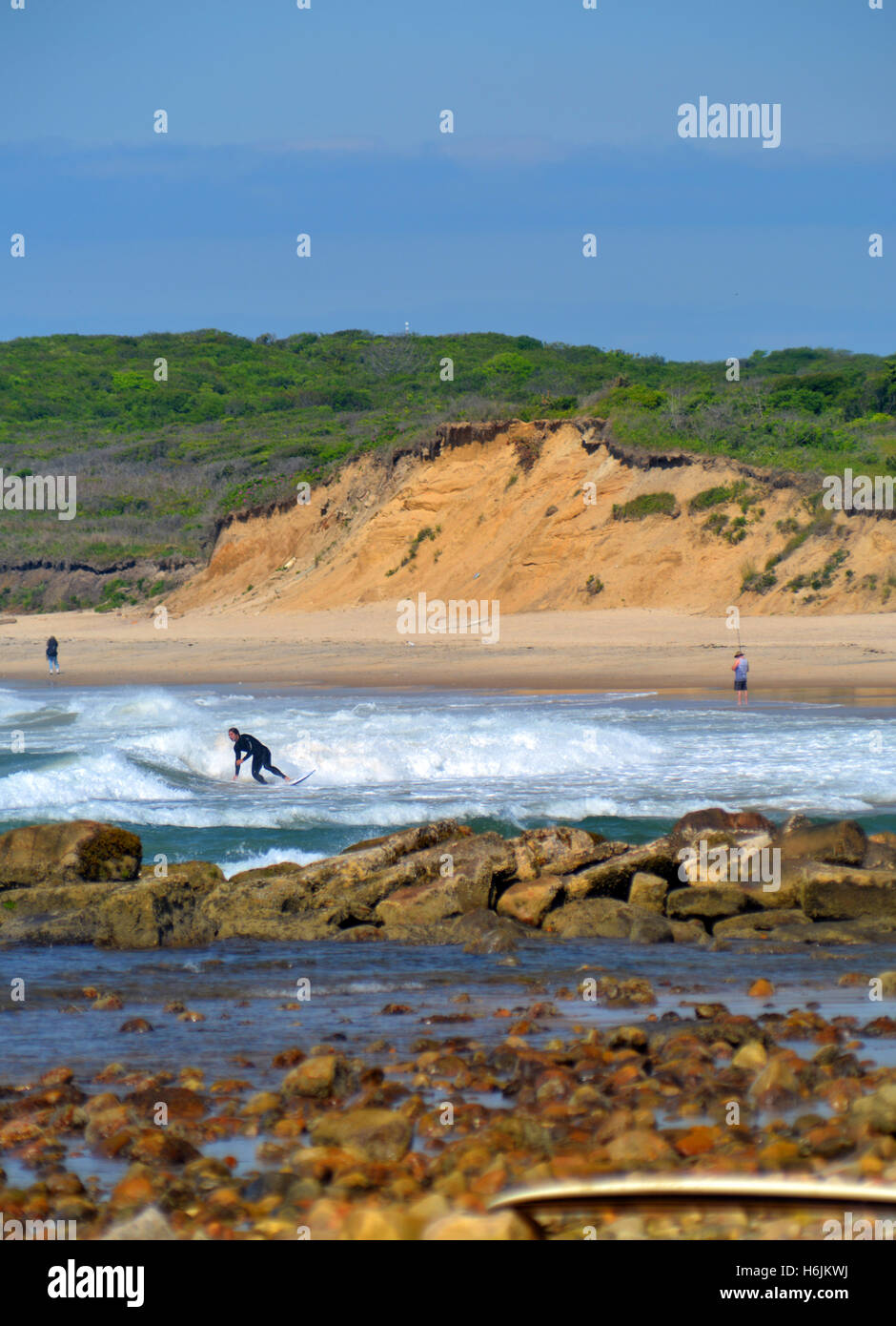 NY-JUNE 13: Unidentified  young man surfing at Ditch Plains beach in Montauk, New York as a is surf casting fishing further down Stock Photo