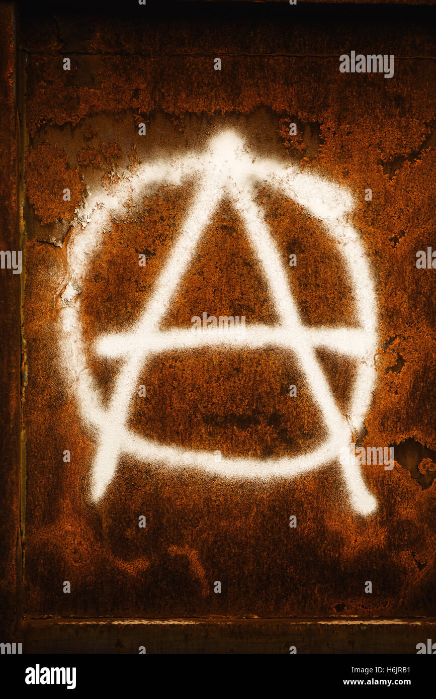 Anarchy symbol graffiti spray painted on grunge corroded metal wall Stock Photo