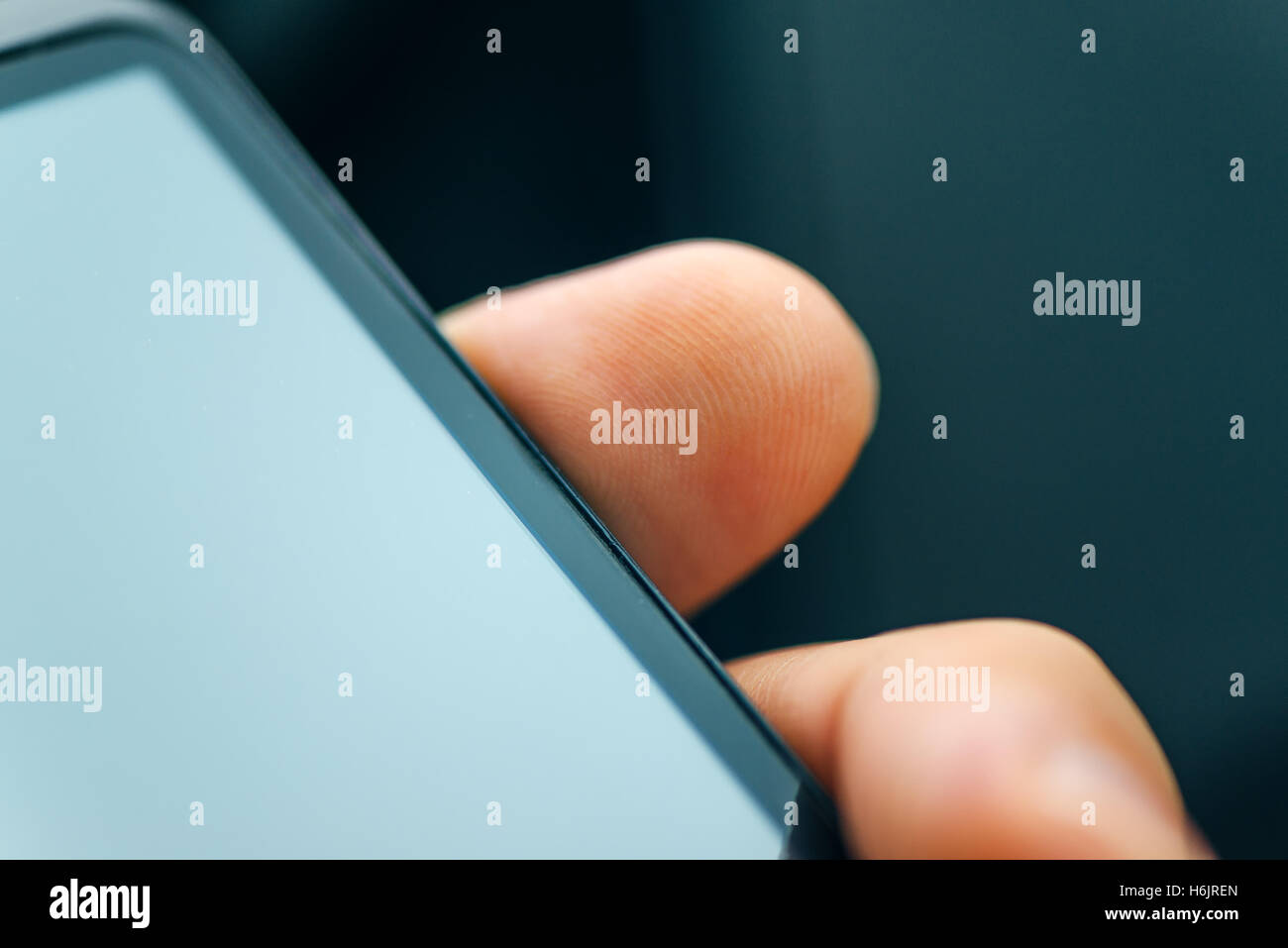 Unlocking smart phone with fingerprint sensor scan, close up with selective focus Stock Photo
