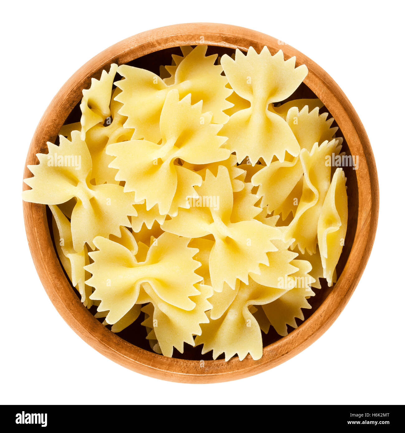 Farfalle pasta in wooden bowl. Uncooked dried durum wheat semolina pasta. Decorative short-cut bow tie or butterfly shaped. Stock Photo