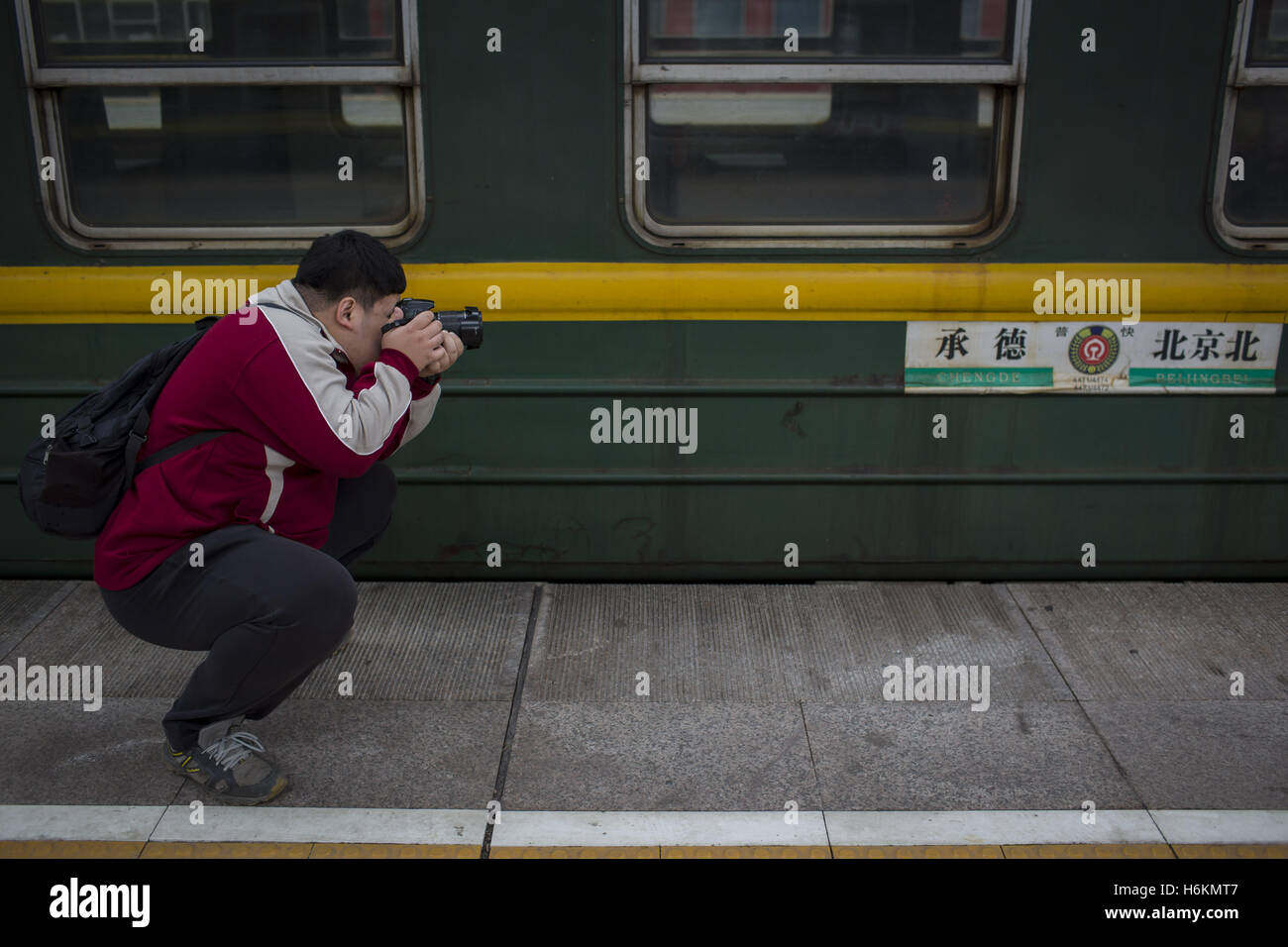 October 27, 2016 - Beijing, china - A man takes photos for the 'green train' at railway station. With China's high-speed rail industry booming around the world, the nation's ''green trains'' are stepping out of China's railways. The ''green trains'', a traditional nickname for Chinese old style passenger trains, have carriages that are usually painted with green color and yellow stripes. Due to the closing of passenger service in Beijing North Railway Station at the 1st day of November, the ''green train'' with series number 4471/4473 which is one of the last remained ''green trains'' in China Stock Photo