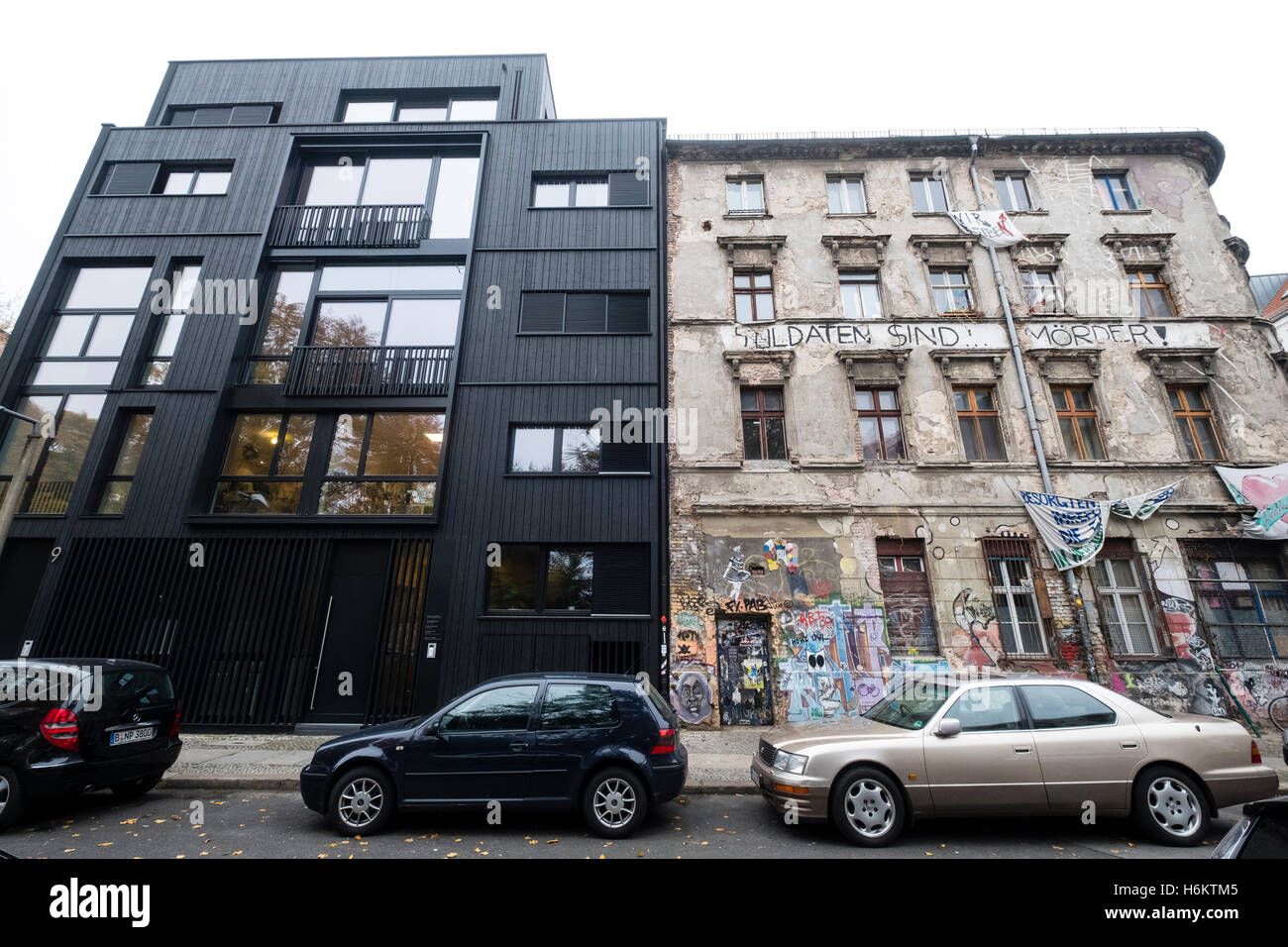Contrast between modern office building and old apartment building used as a squat in Mitte Berlin Germany Stock Photo