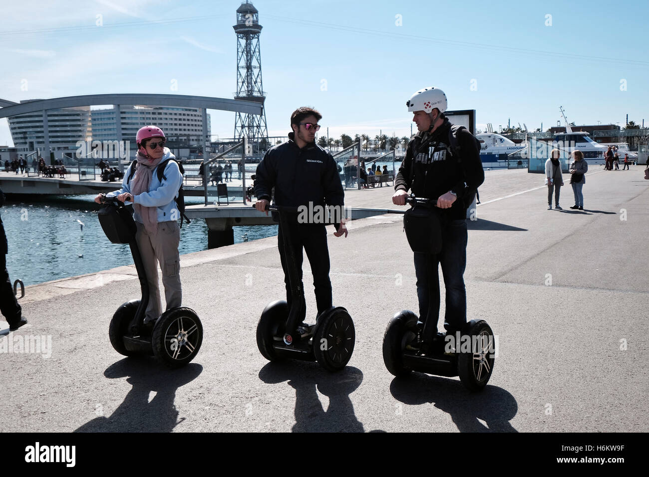 Three travellers using Segway two wheeled vehicles along Port Vell, Barcelona, Spain Stock Photo