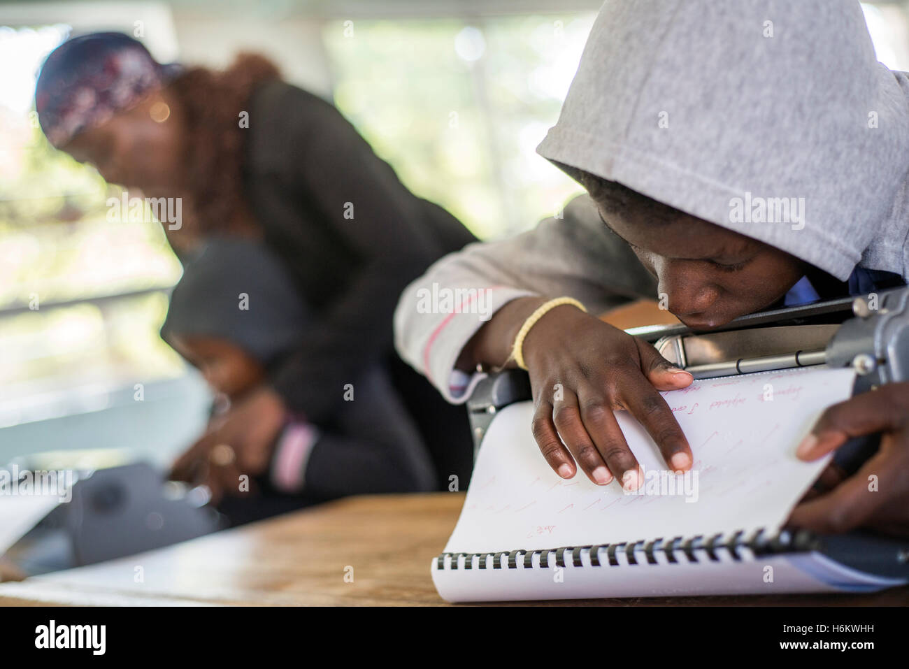 A teacher Esther Washinana helps the visually impaired learner to use Braille typewriter during