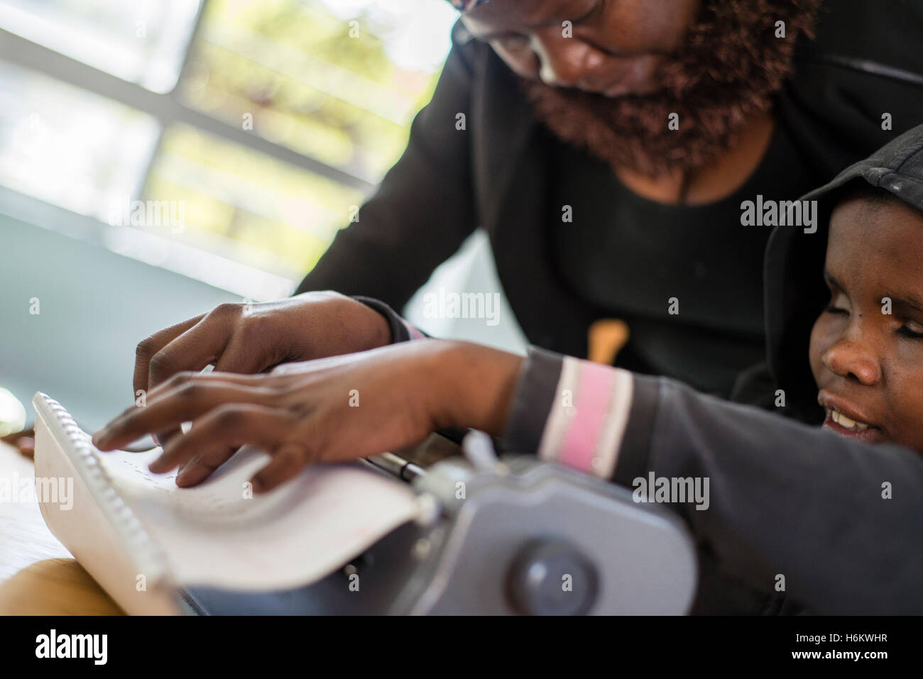 A teacher Esther Washinana helps the visually impaired learner to use