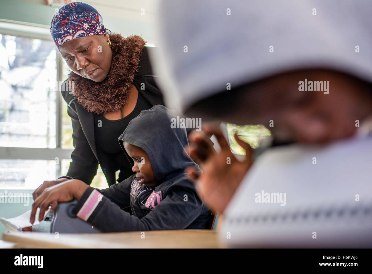 A teacher Esther Washinana helps the visually impaired learner to use