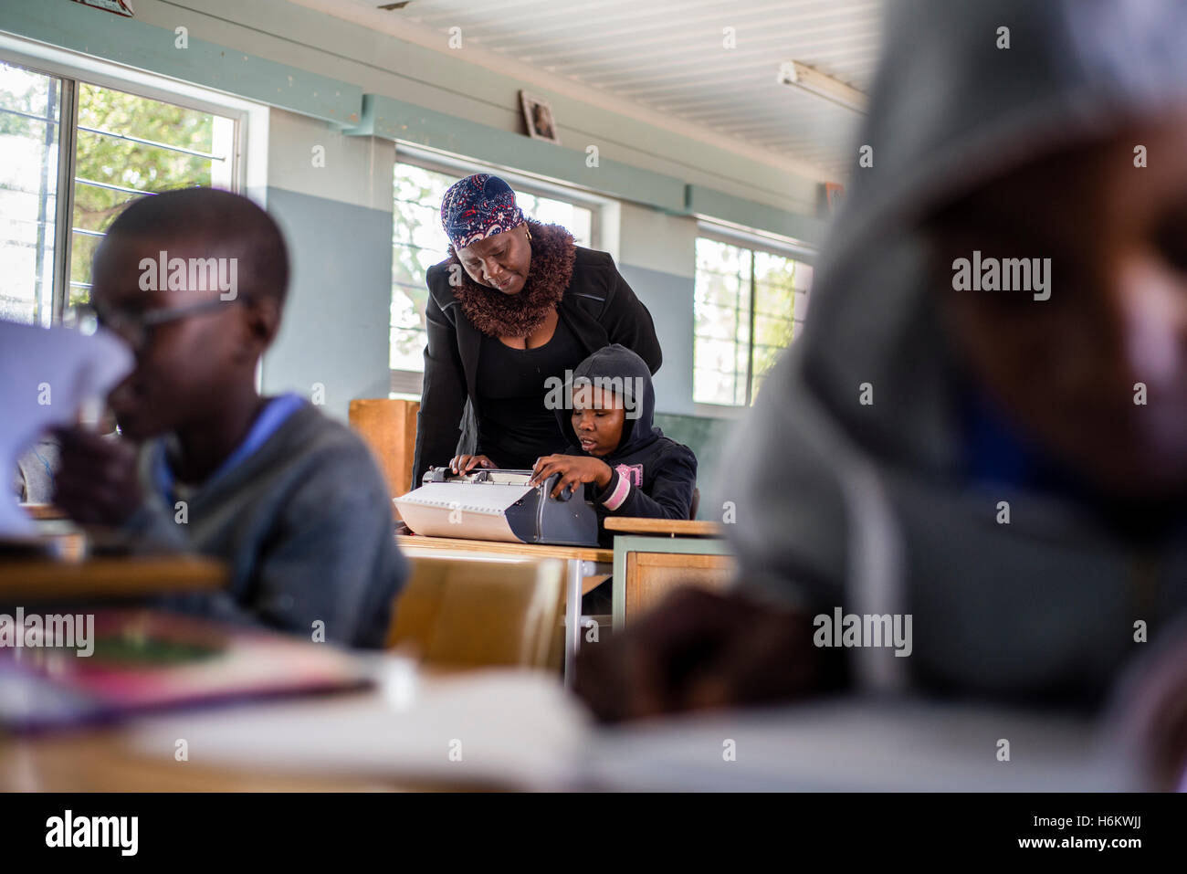 A teacher Esther Washinana helps the visually impaired learner to use