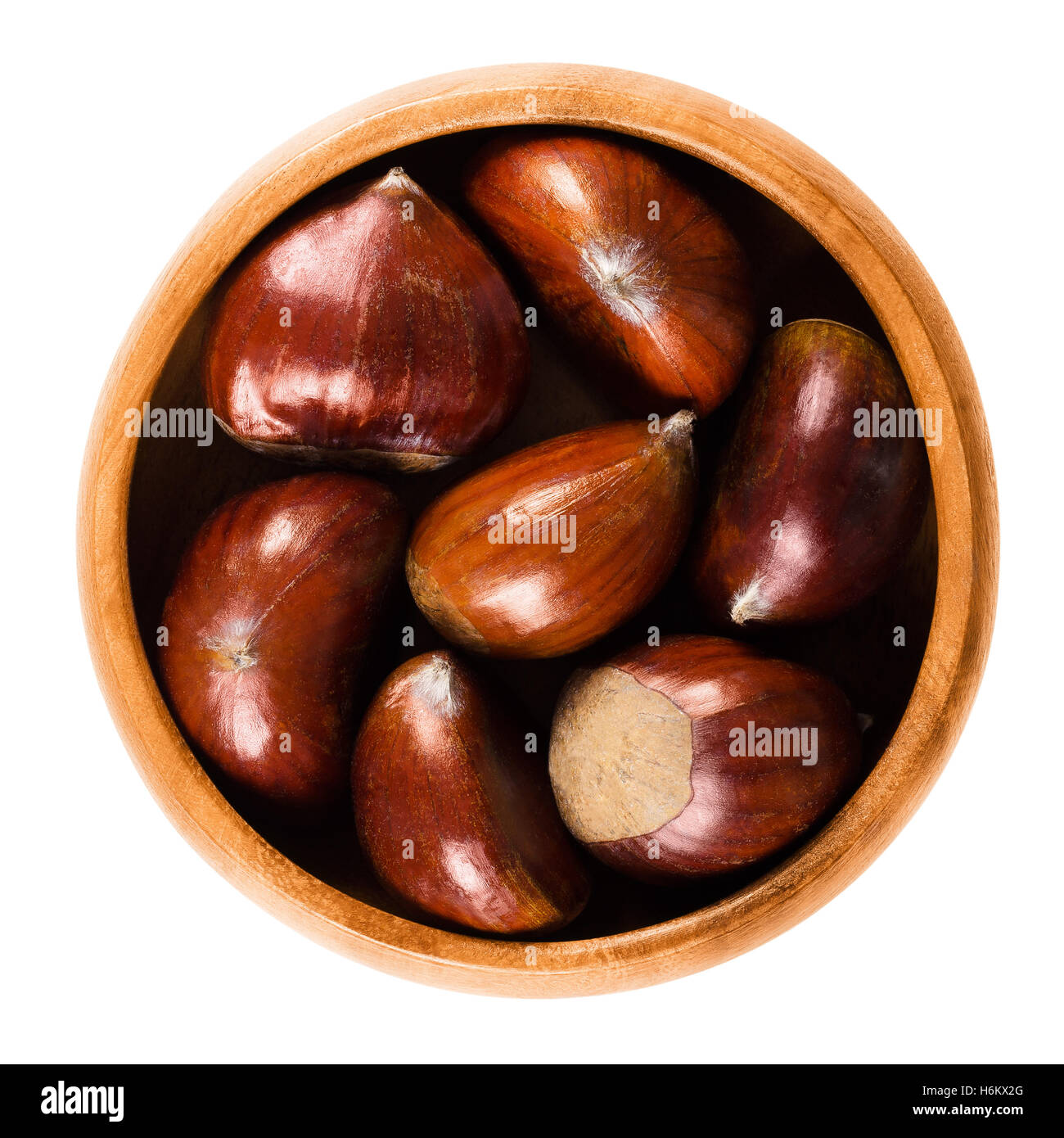 Sweet chestnuts in wooden bowl on white background. Edible seeds or nuts of Castanea sativa, also called marron. Stock Photo