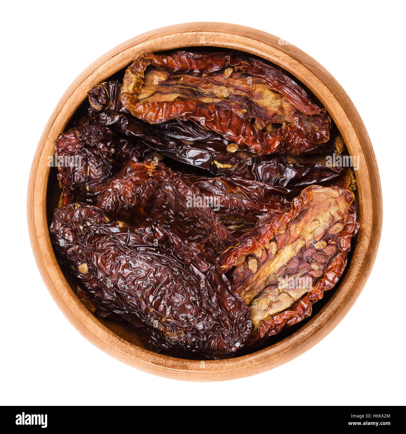 Sun dried tomatoes in wooden bowl on white background. Ripe tomatoes lost most of their water after drying in the sun. Stock Photo