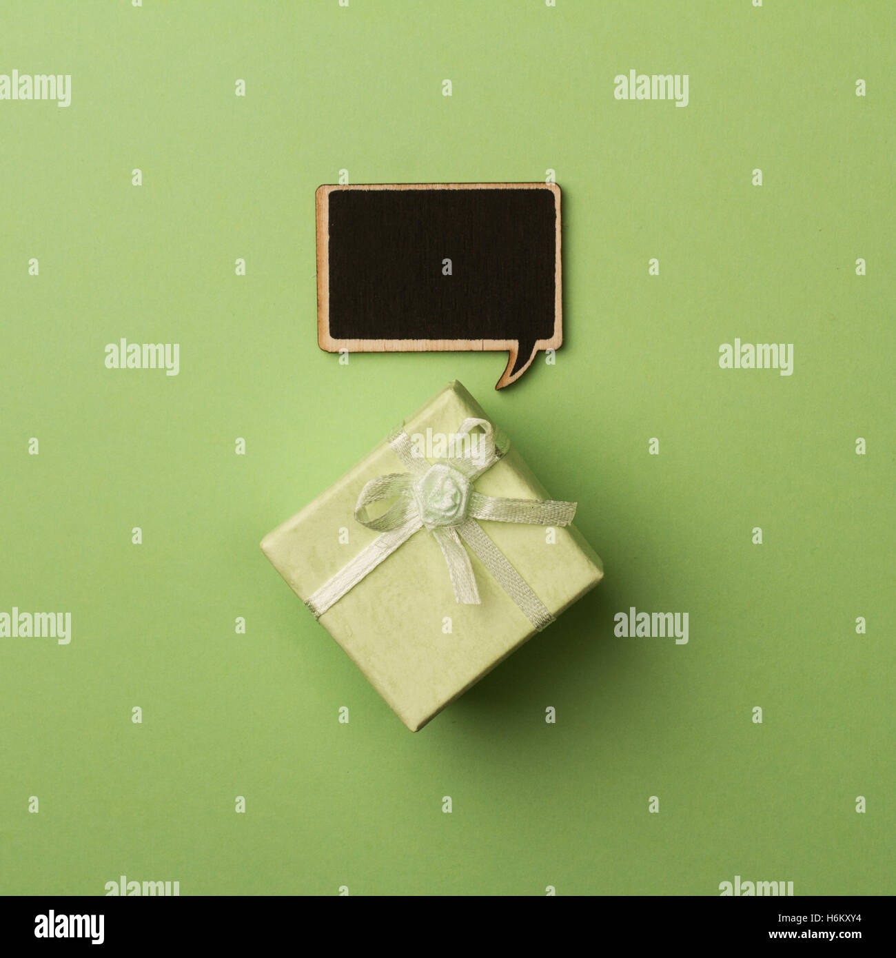 top view of small gift box on green background with wooden black chalk board speech bubble for text Stock Photo
