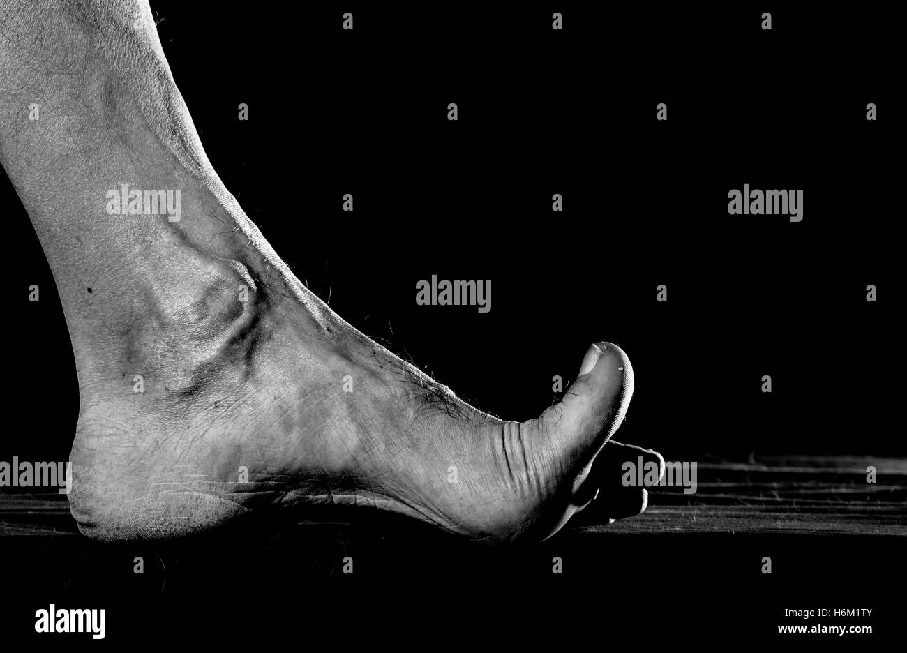 Dirty foot barefooted men against a dark background. Stock Photo