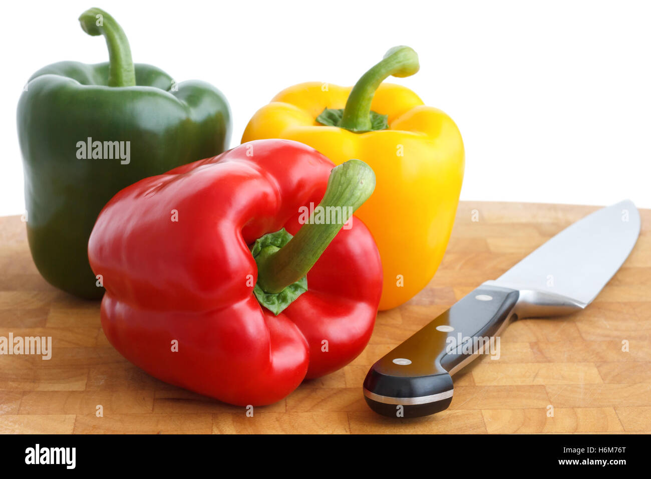 Red, yellow and green peppers on chopping board. With knife Stock Photo ...
