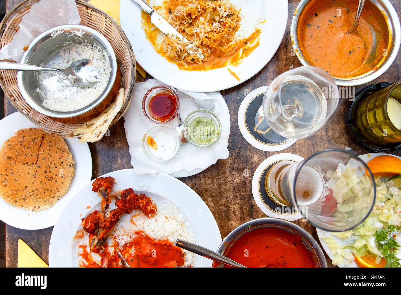 Plates of Indian food leftovers on wooden table from above. Stock Photo