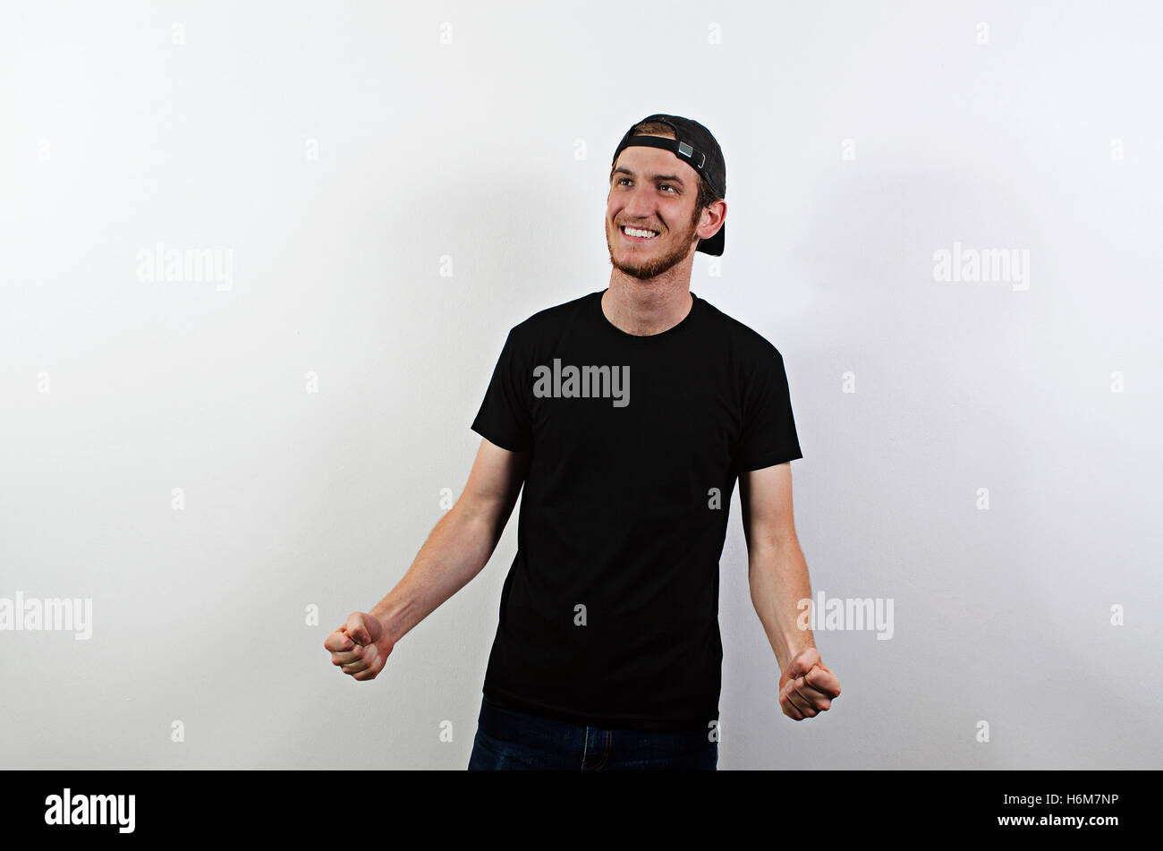 Joyful Happy Smiling Young Adult Male in Dark T-Shirt and Baseball Hat Worn Backwards Stock Photo