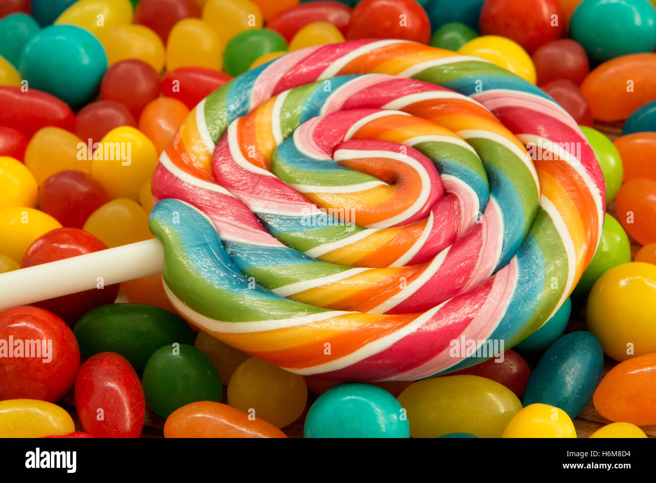 Colorful jelly beans and lollipop close to wallpaper Stock Photo - Alamy
