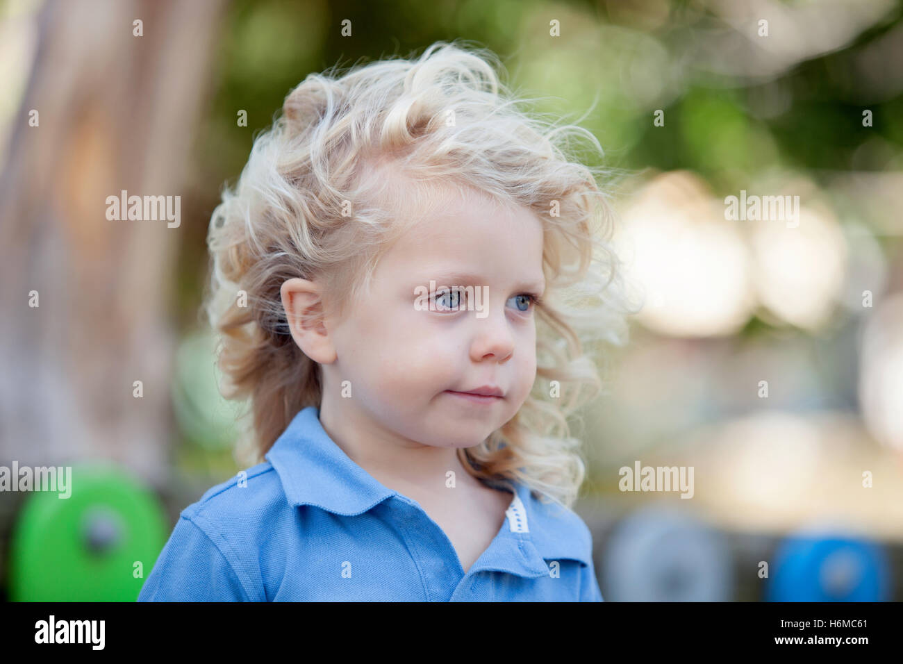 Beautiful boy three year old with long blond hair on a sunny day Stock