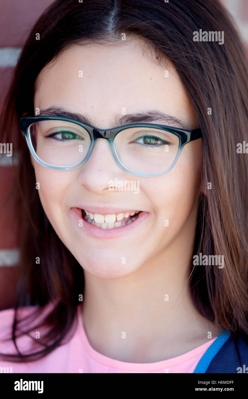 Preteenager girl next to a red brick wall with nice expression Stock Photo